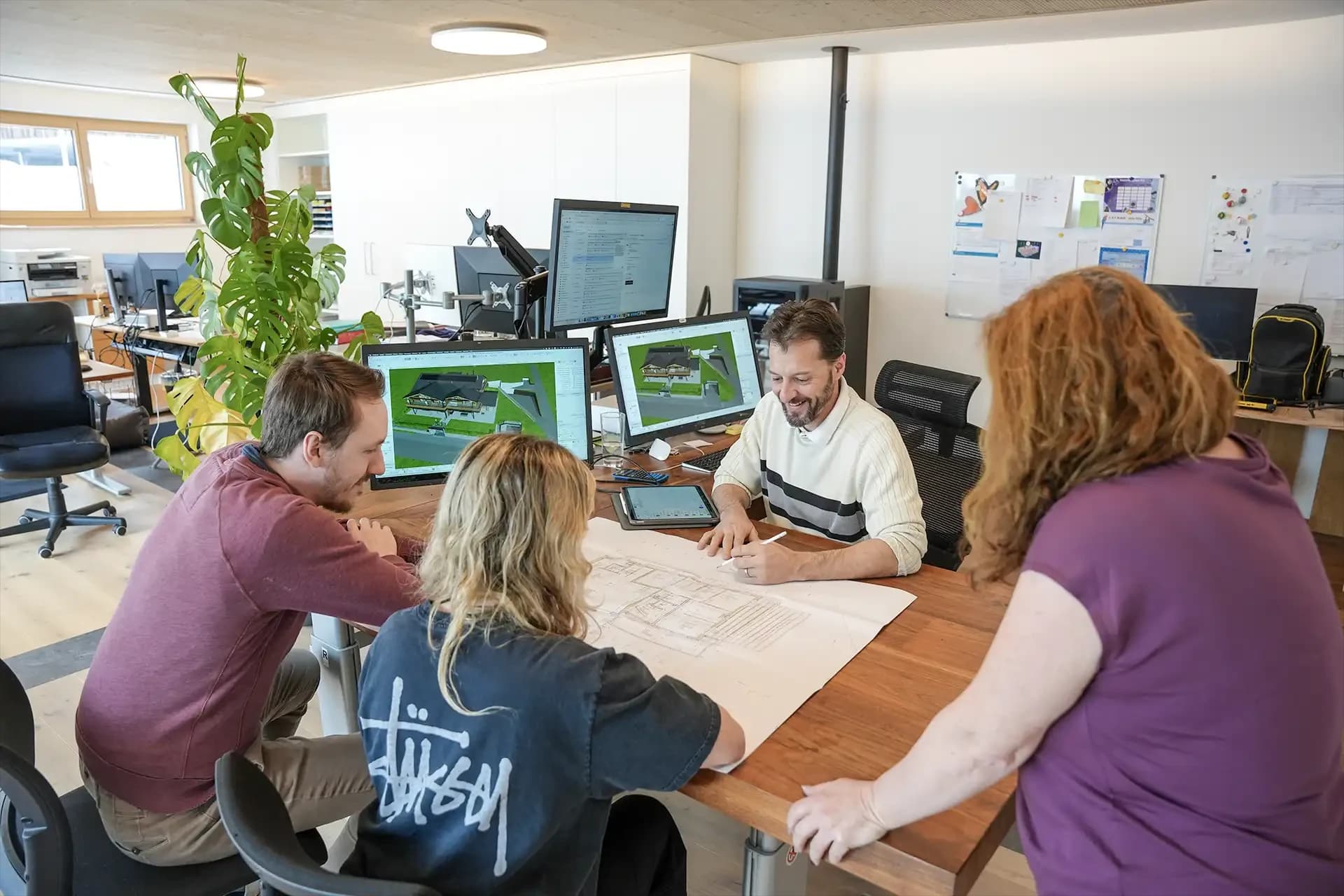 Das Team bespricht ein Projekt am Planungstisch im Büro in Serneus